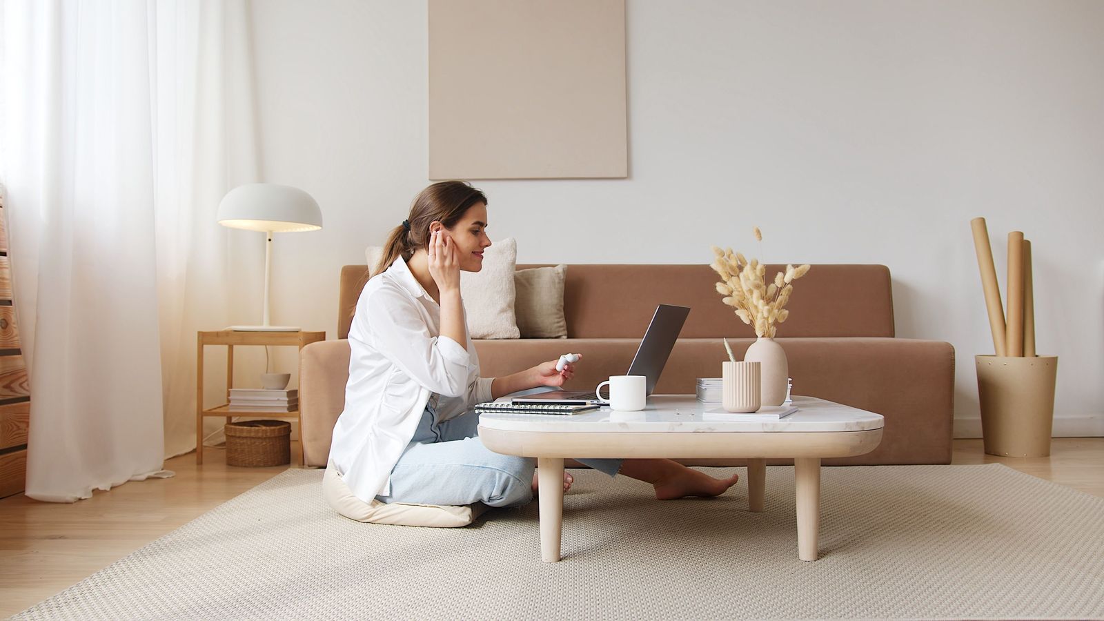 A woman on a video call at a low table in a calm, warm living room
